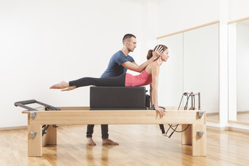 Fototapeta premium Pilates lesson on reformer, personal coaching young beautiful woman