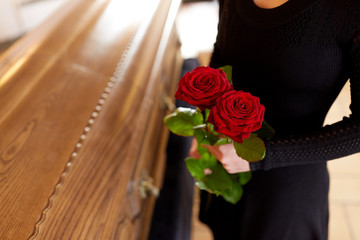 woman with red roses and coffin at funeral