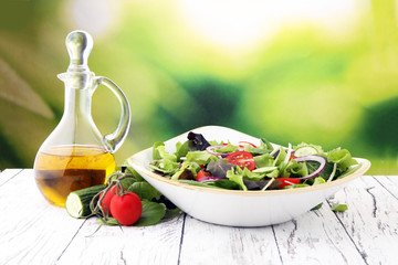 bowl of salad with vegetables and greens, with tomato, cucumber and onions