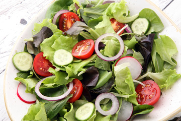 bowl of salad with vegetables and greens, with tomato, cucumber and onions