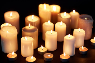 candles burning in darkness over black background