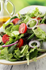 bowl of salad with vegetables and greens, with tomato, cucumber and onions