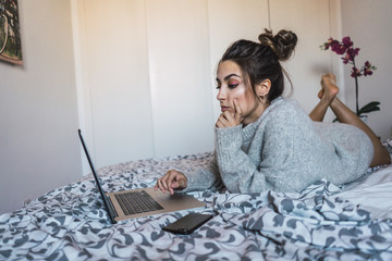 Woman at laptop on bed