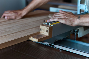 Sawing up of a wooden board on a sliding table saw. Woodworking and carpentry production. Furniture...