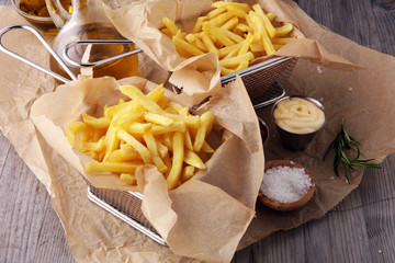 french fries, chips on wooden background with salt