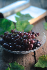 Autumn still life: Grapes with a book on a wooden background.