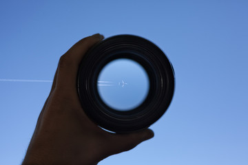 View through spyglass lens to the airplane flying in the sky