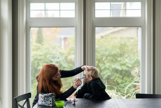 Mother Applying Halloween Make Up For Boys Costume