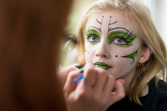 Mother Applying Face Paint Makeup for Little Girl Witch Halloween Costume