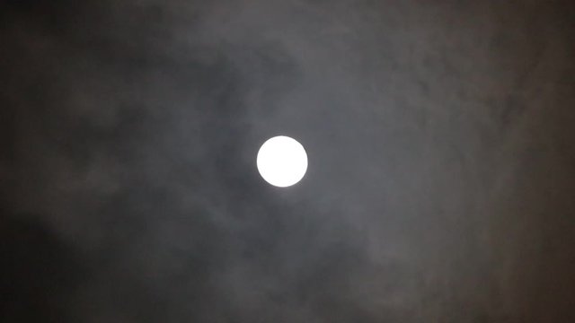 full moon shining with moving clouds in the night sky

