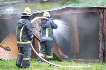 A team of firefighters extinguishes a fire in old wooden buildings