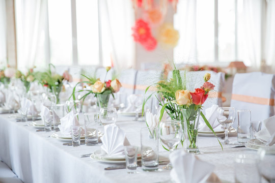 table serving with dishes, glasses and flowers in hall