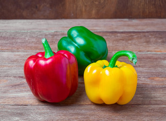 Fresh green, yellow and red pepper on rustic wooden background