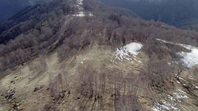 discover sun forward over bare fall woods forest and snow mountain in autumn or winter day. Outdoor sunny nature scape mountains wild aerial establisher.4k drone flight establishing shot