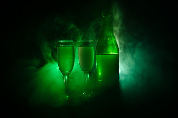 two glasses of wine and bottle over toned foggy background. Image of two wine glasses with champagne the outlines and silhouettes , dark background.