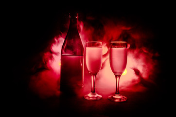 two glasses of wine and bottle over toned foggy background. Image of two wine glasses with champagne the outlines and silhouettes , dark background.