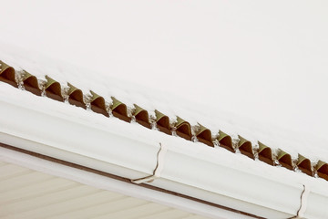 Naklejka premium Snow-covered icy roof overhang with gutter. Frozen drain.