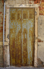 An old rusty metal door in a disused building on the Venetian island of Giudecca
