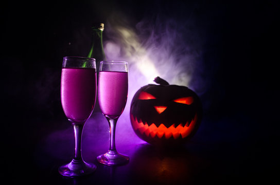 Two glasses of wine and bottle with Halloween - old jack-o-lantern on dark toned foggy background. Scary Halloween pumpkin. Useful as party poster