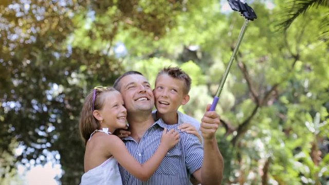 Cute father with children having fun and taking selfie outdoors