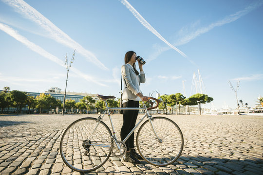 Businesswoman Standing With Her Vintage Bicycle And Drinking A Coffee Outside.