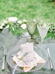 decorated wedding table with beautiful flower composition, glass for wine and plate, outdoor, fine art.