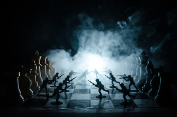 War concept. Silhouettes of soldiers on chessboard. War Concept. Military silhouettes fighting scene on war fog sky background, Chess board game concept of business ideas and competition © zef art