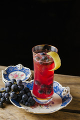 Cranberry color cocktail  garnished with fresh grapes on a vintage plate
