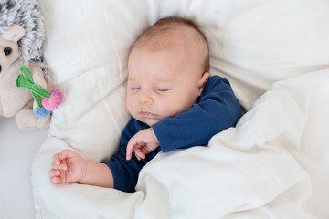 Cute newborn baby boy, lying in bed with cold