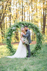 Wedding ceremony outdoors. The groom and the bride on background of wedding arches.