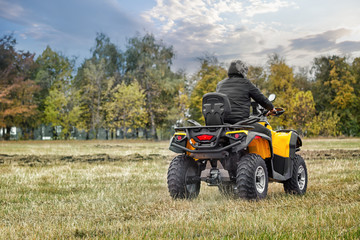 Obraz premium Racer on yellow ATV leaving into the distance