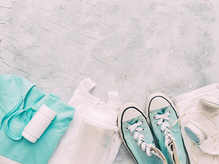 Workout kit. Athlete's set with female clothing. Flat lay sport shoes, earphones  on gray background. Concept healthy lifestyle