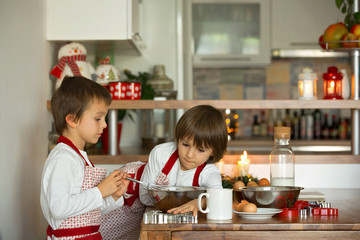 Two sweet children, boy brothers, preparing gingerbread cookies for Christmas