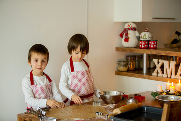 Two sweet children, boy brothers, preparing gingerbread cookies for Christmas
