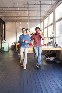 A team of two professionals or entrepeneurs drinking coffee in their office, looking at the camera