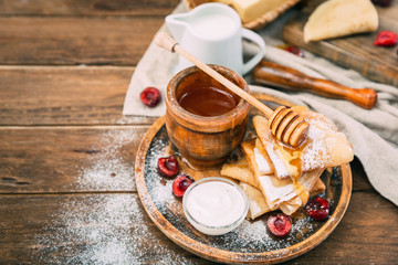 Fresh homemade crepes with honey and berries over rustic background