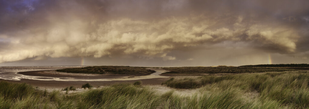 Storm clouds and rainbow at sunset. Holkham, Norfolk, UK.