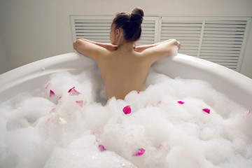 girl lying on belly in a large round white bath