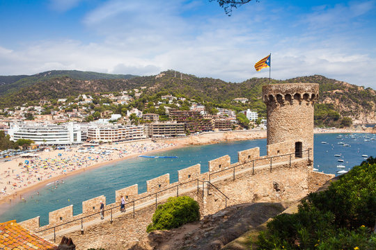 View from the castle hill towards the beach. Castle tower and fragment of walls. Tossa de Mar town on the Costa Brava, Hispania.