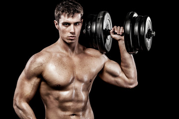 Naklejka na ściany i meble Athletic shirtless young sports man - fitness model holds the dumbbell in gym. Copy space fore your text.