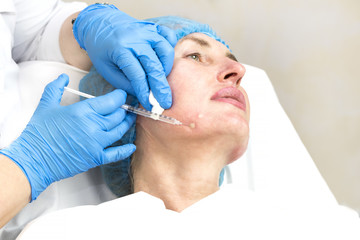 Obraz na płótnie Canvas An adult woman undergoes cosmetic surgery in a beauty salon