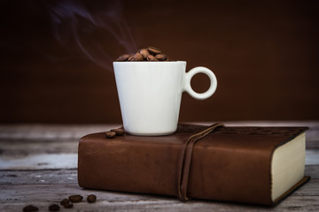 tazza di caffè fumante appoggiata su libro 