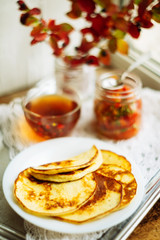 Home-made breakfast or brunch: american style pancakes served with berries and sugar powder on vintage metal tray with a cup of black tea