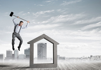 Manager man crashing stone home as symbol for real estate insurance