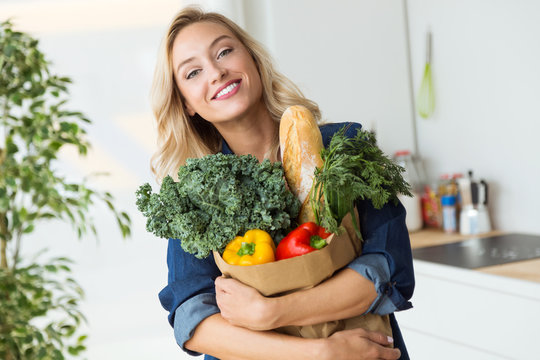 Beautiful young woman grocery shopping bag with vegetables at home.