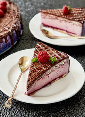 Piece of raspberry cream mousse cake covered with chocolate glaze