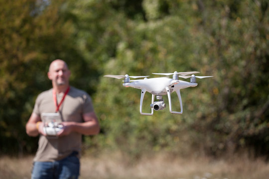 Young man with flying drone in the park.  Man with remote controller in his hands taking aerial photos and videos