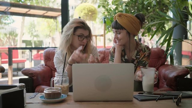 Two young beautiful professionals, female freelancer and business lady have meeting in downtown city centre cafe, discuss project and drink coffee, casual atmosphere of startup