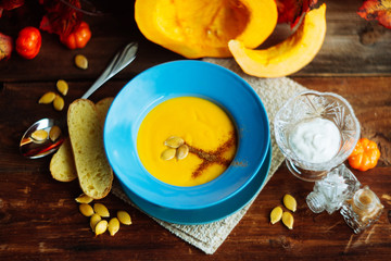 Pumpkin and carrot soup with cream and parsley on dark wooden background Top view