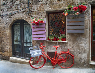 Fototapeta na wymiar Red bike in a traditional Italian medieval town, Tuscany, Italy.